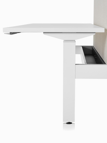 Vista de perto de um sistema de mesas com regulagem de altura Nevi Link com superfície de trabalho retangular branca, base branca, passador de cabos básico e tela cinza.
