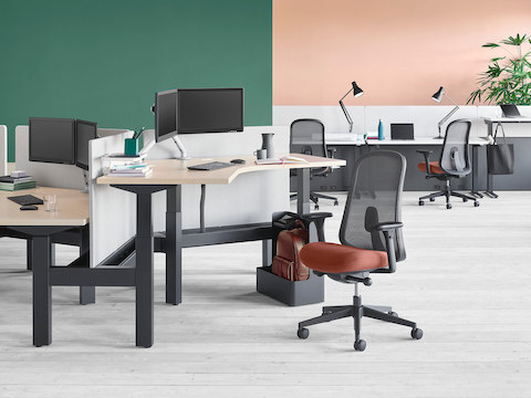 Configuração de escritório com sistema de mesas com regulagem de altura Nevi Link com superfícies de trabalho de 120 graus em primeiro plano e Canvas Channel com mesas com regulagem de altura Nevi ao fundo.