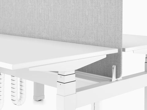 Gros plan d’un bureau Nevi Link, montrant un écran de séparation en tissu gris monté entre deux bureaux blancs adossés.