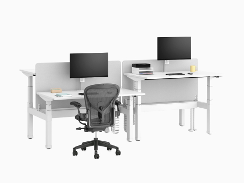 Nevi Link zit-sta configuratie met vier bureaus in wit met grijze stoffen schermen en twee bureaus verhoogd tot stahoogte, Lima monitorarmen en een Aeron-stoel. Nevi Link zit-sta configuratie met vier bureaus in wit met grijze stoffen schermen en twee bureaus verhoogd tot stahoogte, Lima monitorarmen en een Aeron-stoel.