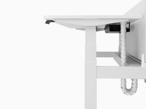 A close-up profile view of a white Nevi Link desk and grey screen showing the T-shaped leg and cable tray under the work surface.