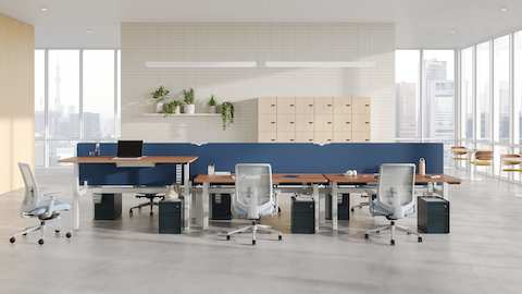 A six desk configuration of Nevi Sit-to-Stand Desks with blue fabric screens, and Trac pedestals in Nightfall with metal drawer pulls.