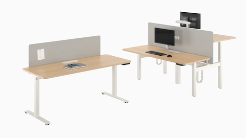 A freestanding Nevi Sit-to-Stand Desk next to a back-to-back two-desk configuration.