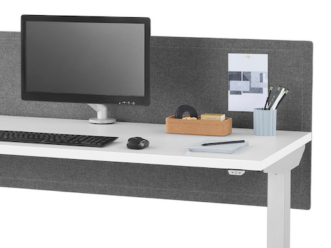 Primer plano de un escritorio elevado Nevi con una superficie en blanco, patas plateadas, pantalla en género gris y brazos articulados para monitor Flo.