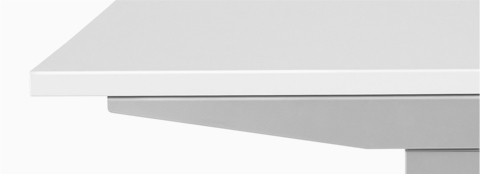 A close-up view of a Nevi standing desk with a white surface and silver legs. 