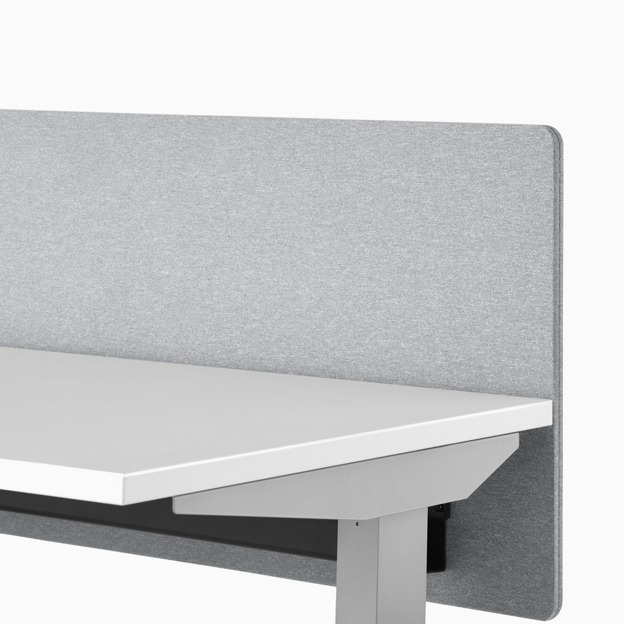 A close-up view of a gray fabric screen attached to the surface of a Nevi standing desk.