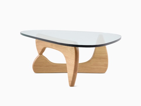 Una mesa auxiliar Noguchi con tapa de vidrio con forma libre y base curva en madera.