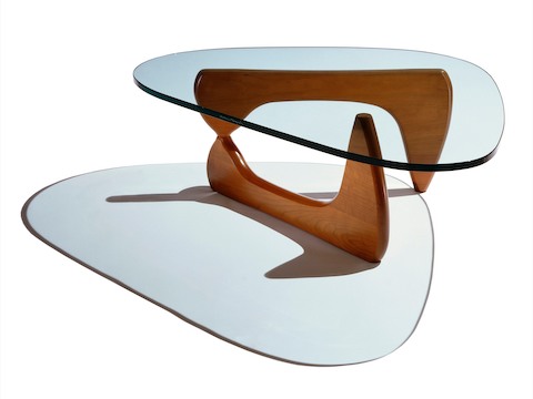 Una mesa auxiliar Noguchi con tapa de vidrio con forma libre y base curva en madera con acabado intermedio.