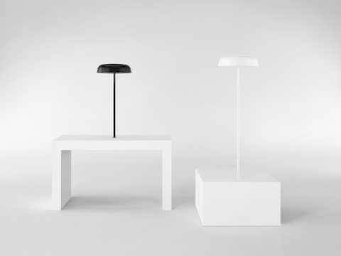 Black and white Ode Lamps, both mounted on surfaces of two different heights.