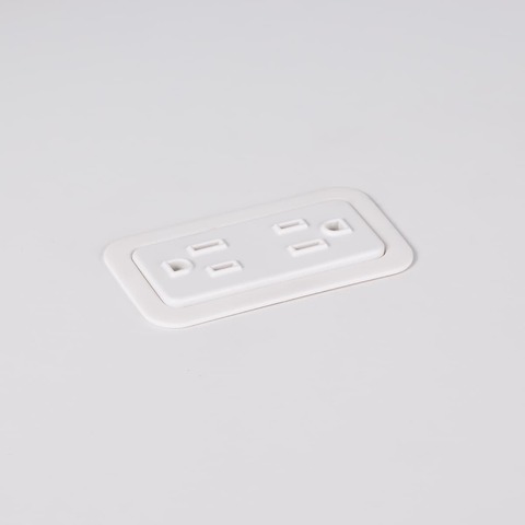 A close-up view of Logic Mini with two power outlets integrated into the top of a white laminate work surface.