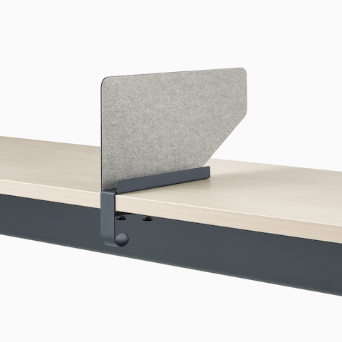 A dark blue OE1 Boundary Screen with grey liner attached to an OE1 Communal Table with light brown surface, viewed from an angle.