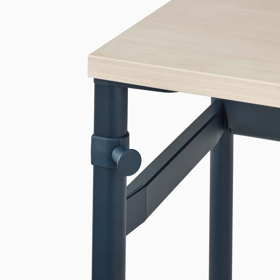Close up image of a dark blue OE1 Communal Table with light brown surface and dark blue bag hook.