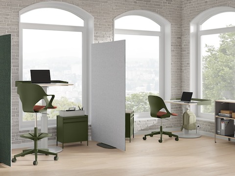 Oficina luminosa con pantallas curvas OE1 verdes y grises, carritos de almacenamiento OE1 verdes, silla Zeph verde y mesas Sit-to-Stand OE1.