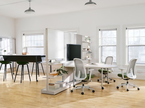 Paredes móviles OE1 en gris con una Mesa para reuniones en grupo OE1 con sillas Lino en gris y verde en el frente, con una Mesa comunitaria OE1 en negro al fondo.