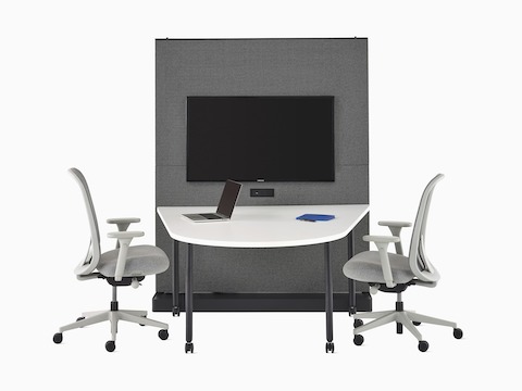 Uma Agile Wall OE1 preta e cinza com peças em tecido para afixar tachas e mostruário, com uma Mesa de junção OE1 branca e duas cadeiras Lino cinza.