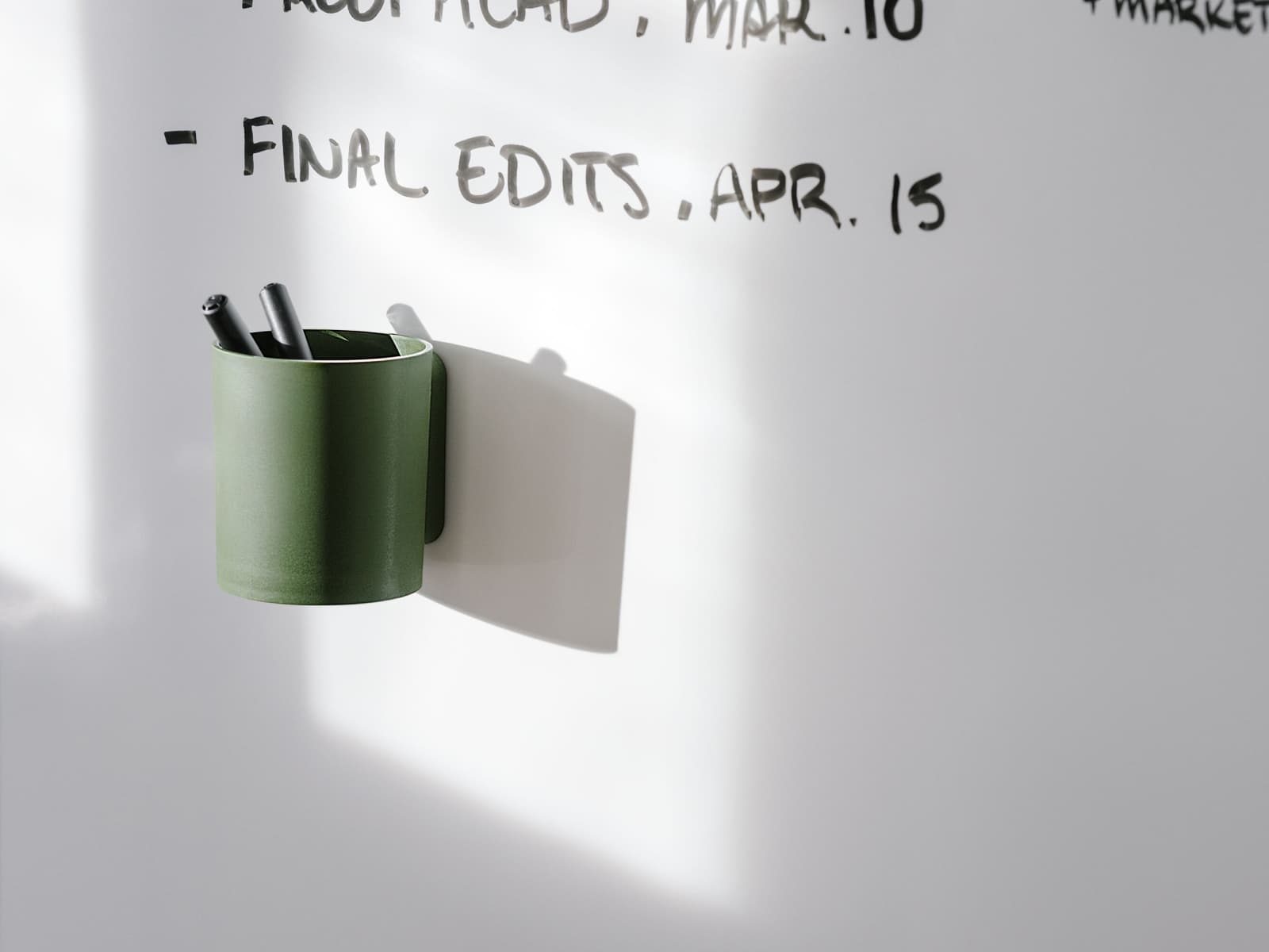 Um Porta lápis OE1 verde afixado a um quadro branco OE1.