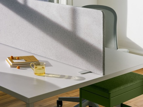 Una mesa rectangular OE1 en blanco con una Pantalla portátil OE1 en gris y un Carrito de almacenamiento OE1 en verde.