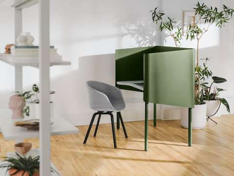 Uma cadeira Hay About A Chair cinza em um Nook OE1 verde, com uma Agile Wall OE1 cinza com prateleiras completas em primeiro plano.