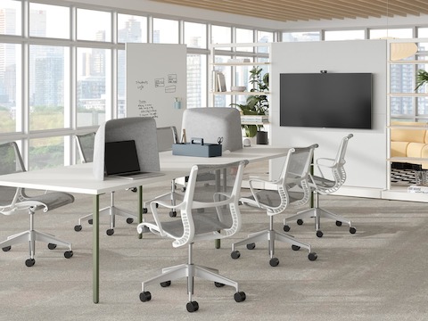 Open floor office with an OE1 Communal Table, OE1 Agile Walls, OE1 Mobile Easel, and Chadwick Sofa. Bureau ouvert avec une table de travail partagée OE1, des murs flexibles OE1, un chevalet mobile OE1 et un canapé Chadwick.