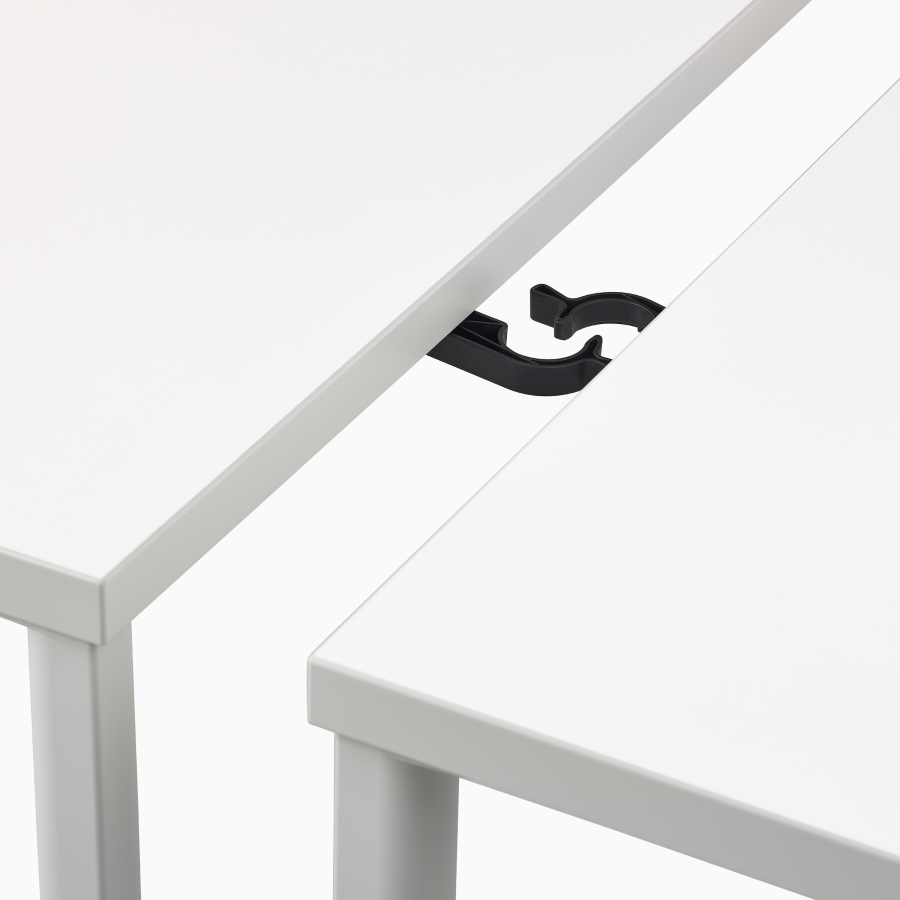 Close up image of two white OE1 tables with two black ganging connectors, viewed from above.