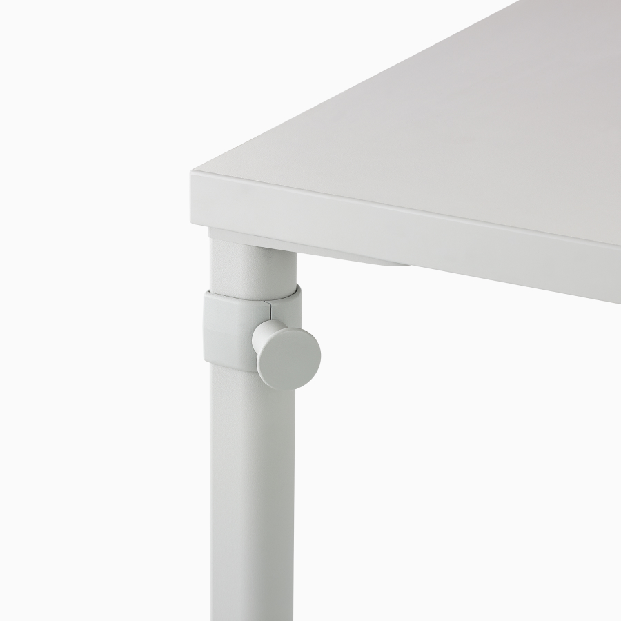 Close up image of a white OE1 table with cable routing through a leg cable manager to the floor.
