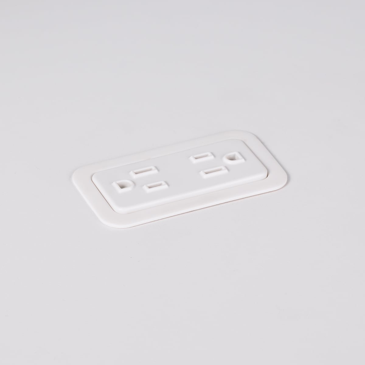 A close-up view of Logic Mini with two power outlets integrated into the top of a white laminate work surface.