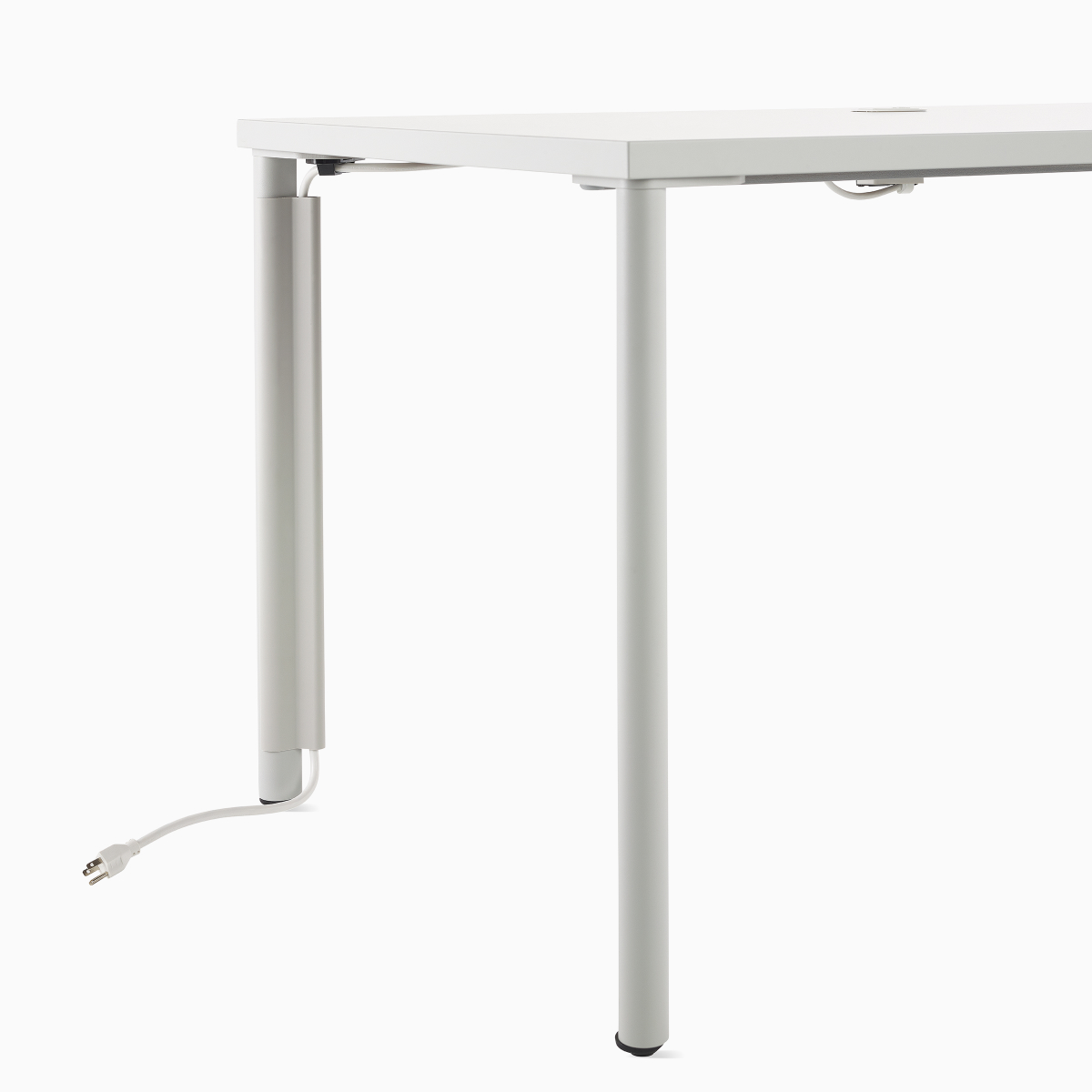 Close up image of a white OE1 Rectangular Table with cable routing through a leg cable manager to the floor.