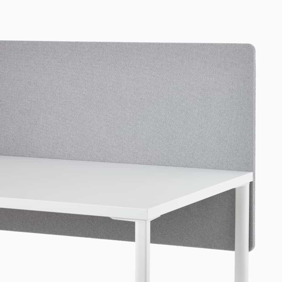Primer plano de una mesa rectangular OE1 en blanco con pantalla en género gris sujetable a superficies.