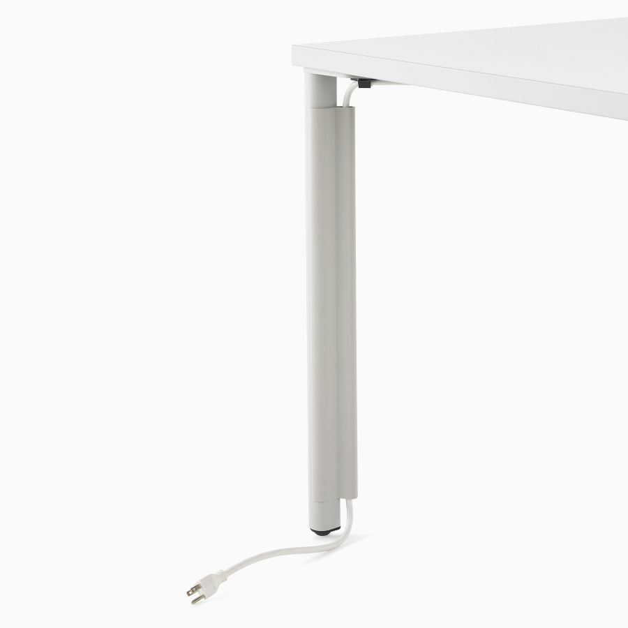 Close up image of a white OE1 table with cable routing through a leg cable manager to the floor.