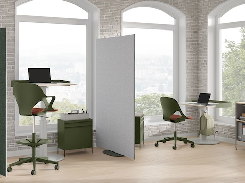 Oficina luminosa con pantallas curvas OE1 verdes y grises, carritos de almacenamiento OE1 verdes, silla Zeph verde y mesas Sit-to-Stand OE1.