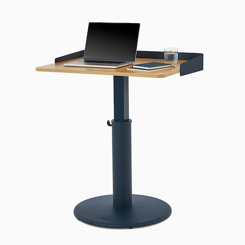 OE1 Sit-to-Stand Table with blue base and brown rectangular surface at a standing height, viewed from a front angle. Rechteckiger OE1 Sitz-Steh-Schreibtisch mit blauem Untergestell und brauner Oberfläche in Stehhöhe, von vorne betrachtet.