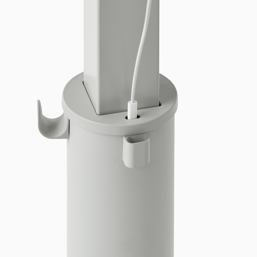 Detail of a grey OE1 Sit-to-Stand Table column with USB-C port with cable plugged in, and a bag hook and cable management clip.