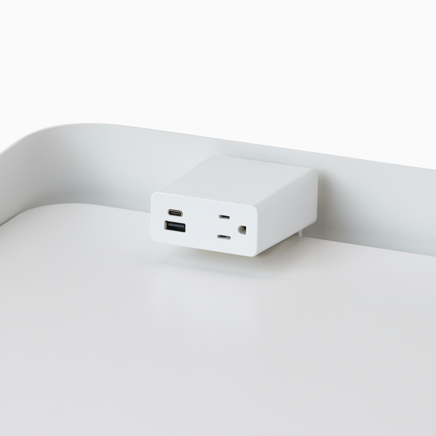 Detalle de una unidad Logic Mini blanca montada sobre una superficie de mesa Sit-to-Stand OE1 blanca con pantalla envolvente gris.