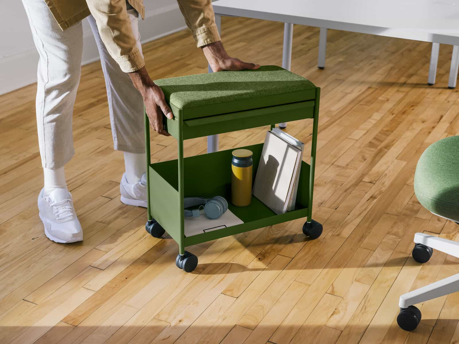 A person moving a green, individual OE1 Storage Trolley with casters.