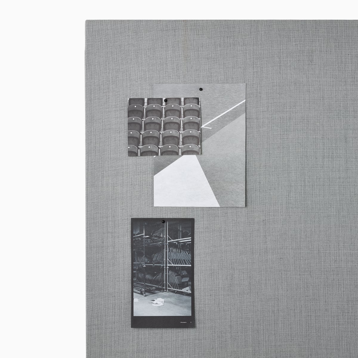 Imagem aproximada de fotos afixadas a um quadro de projeto OE1 em tecido cinza.