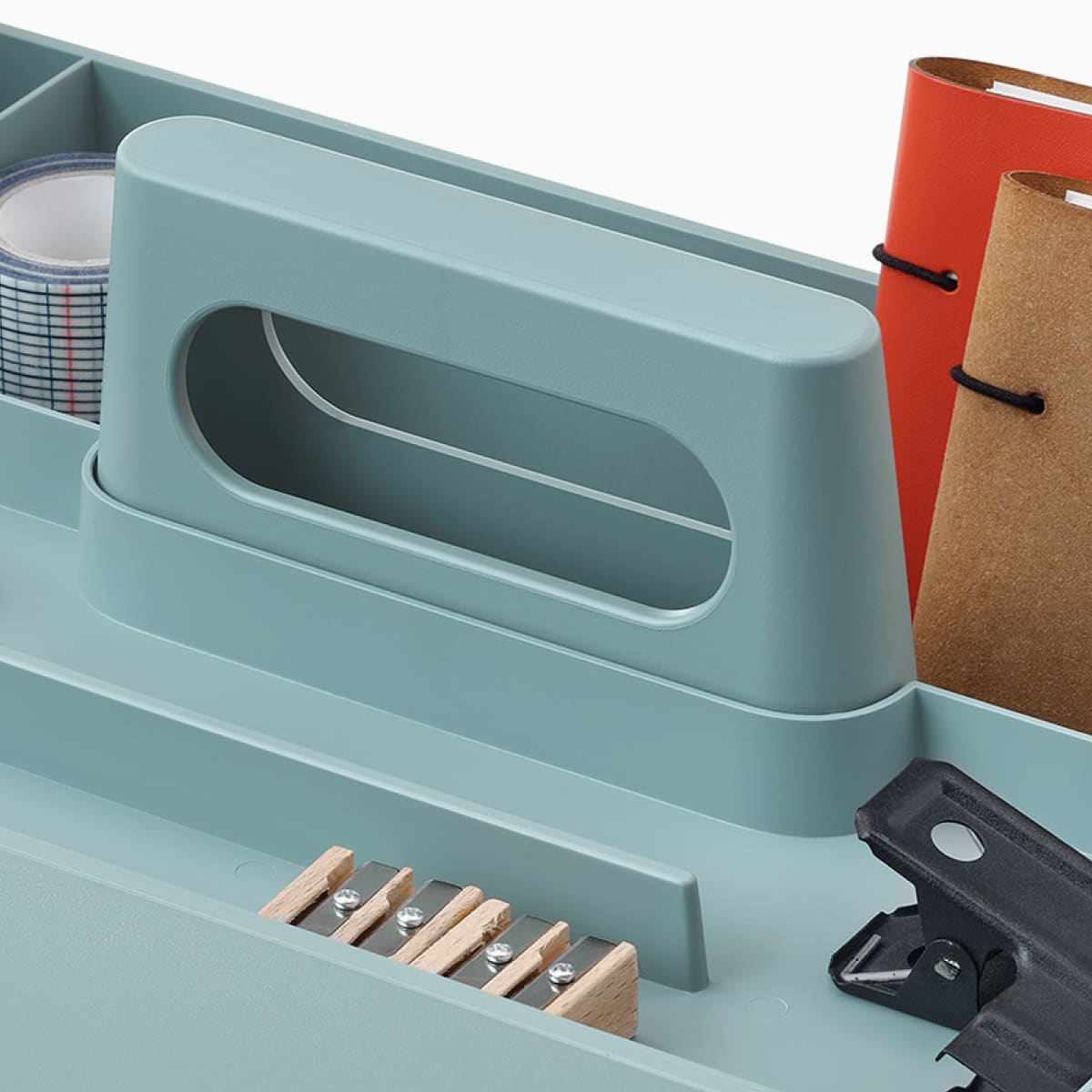 OE1 Workbox azzurra con matite, blocchi per appunti e altri oggetti personali, visti da un'angolazione.