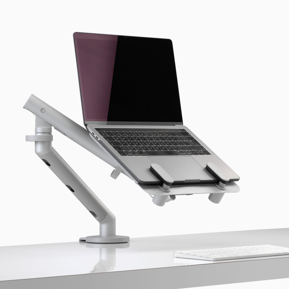 An open laptop raised to eye level and supported by an Ollin Laptop Mount and Flo Monitor Arm.