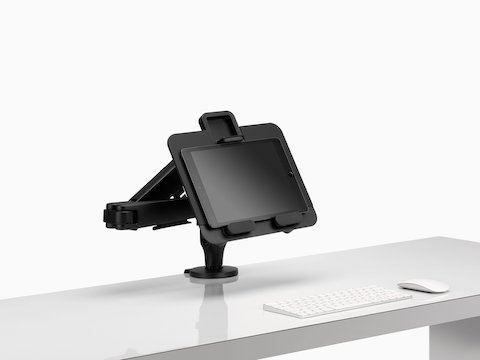 Een tablet ondersteund door een Ollin-laptop en tabletsteun die is aangesloten op een zwarte Ollin-monitorarm.