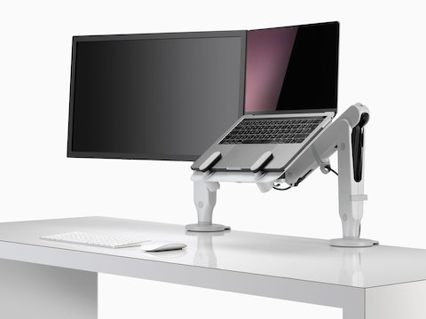 Een monitorscherm en een open laptop verhoogd op oogniveau en ondersteund door een Ollin-laptopsteun en Ollin-monitorarmen.