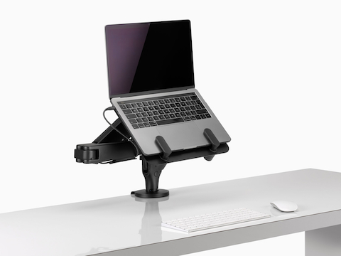 Offener Laptop in erhöhter Position, getragen von einer schwarzen Ollin Laptop-Halterung an einem Ollin Monitorarm.