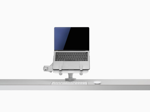 Vooraanzicht van een open laptop verhoogd en ondersteund door een Ollin-laptopsteun en Tabletsteun die is aangesloten op een Ollin-monitorarm.