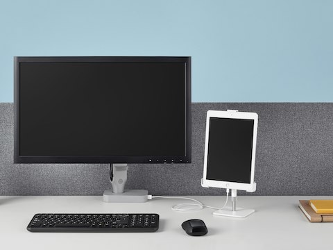 Een Flo Power Hub dient als basis voor een Ollin-monitorarm tijdens het opladen van een tablet die wordt ondersteund door een Tabetha-tabletbevestiging.