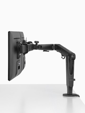 Two Ollin Monitor Arms, one connected to a Flo Power Hub, elevate a pair of monitors off the surface of a sit-to-stand table.