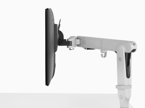 Vista de perfil de um monitor conectado a um braço branco de monitoração Ollin.