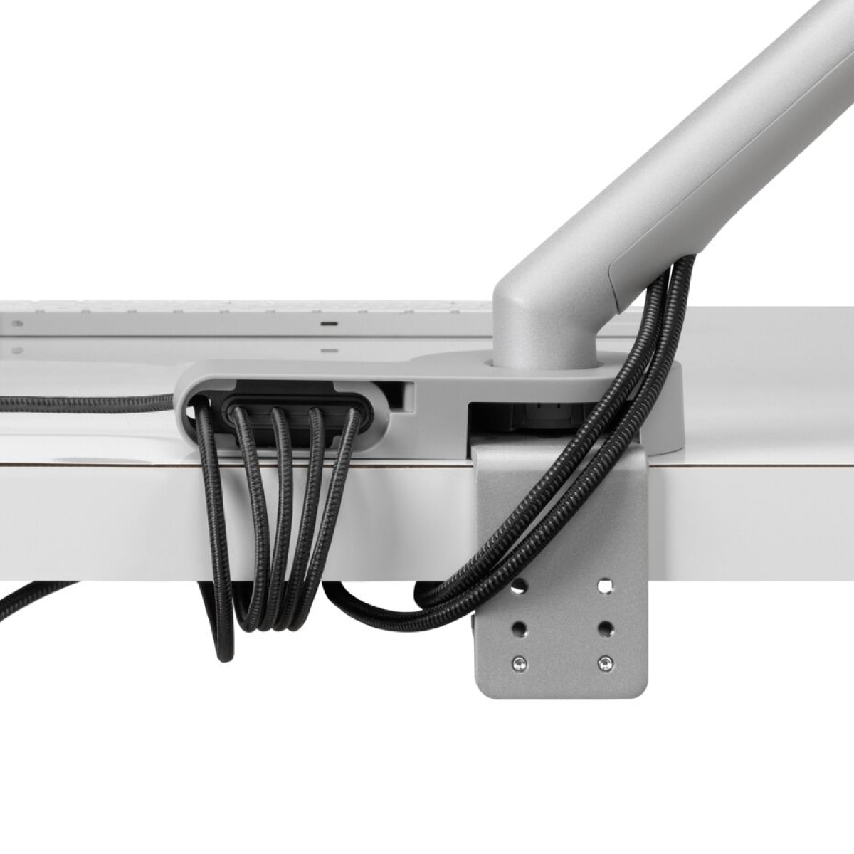 Vista posterior de cables de energía y datos conducidos desde el brazo articulado para monitor conectado, a través del módulo de conectividad Ondo y el micro soporte en forma de bucle debajo del escritorio.