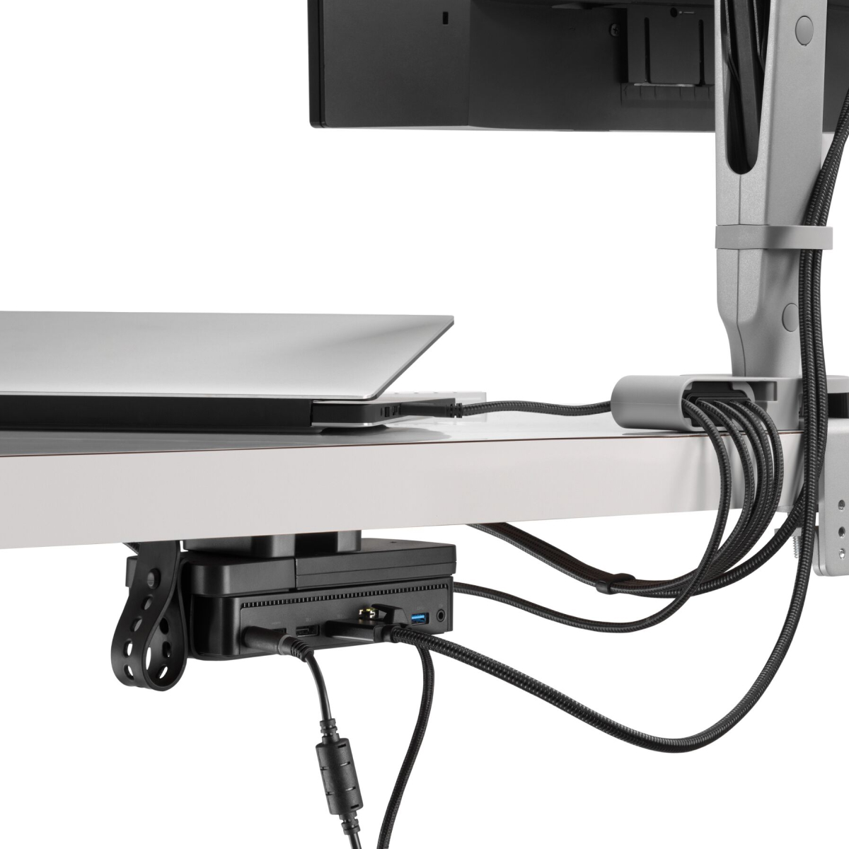 Schräge Rückansicht eines Monitors mit Strom- und Datenkabeln, die vom zugehörigen Monitorarm und durch ein Ondo Verbindungsmodul zu einem Laptop und einer Loop Micro Gerätehalterung unter einem Schreibtisch verlaufen.