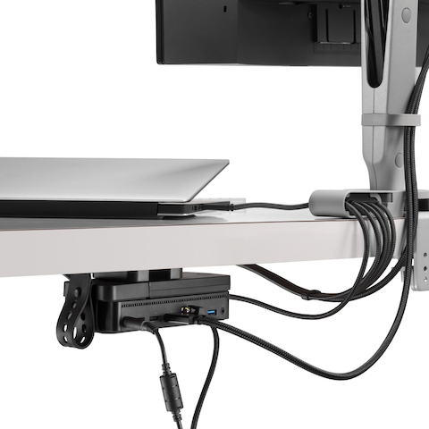 Back angled view of a monitor screen with cables routed from the connected monitor arm and through an Ondo Connectivity Module to a Laptop and Loop Micro Mount under a desk.