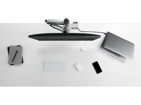 Vista dall'alto di un braccio porta monitor Wishbone integrato con un modulo di connettività Ondo su una scrivania d'ufficio e collegato a un laptop e a un telefono.