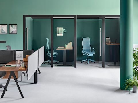 Dos salas Overlay cerradas con un escritorio de altura ajustable y sillas a cada lado ubicados en segundo plano. Una estación de trabajo Canvas se encuentra en primer plano.
