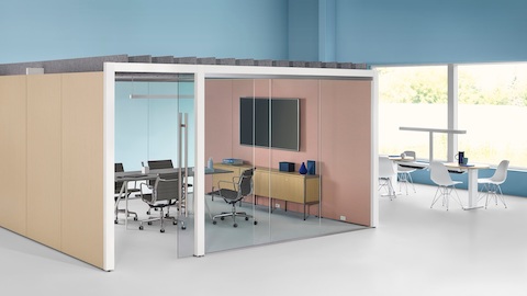 An enclosed Overlay meeting room with two glass walls and two laminate walls with a conference table and four chairs inside. An enclosed Overlay meeting room with two glass walls and two laminate walls with a conference table and four chairs inside.
